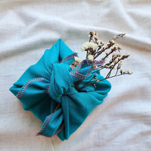 Load image into Gallery viewer, Turquoise fabric gift wrap tied in Japanese furoshiki style with dried white flowers
