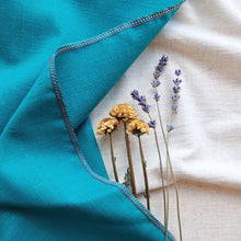 Load image into Gallery viewer, Turquoise recycled fabric gift wrap draped over white fabric background, with yellow and blue dried flowers tucked under