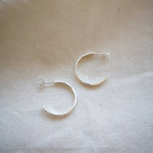 Load image into Gallery viewer, Side profile of textured simple silver hoop earrings on neutral background