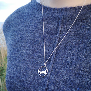 Cornish map necklace worn on blue jumper on Cornish cliffs