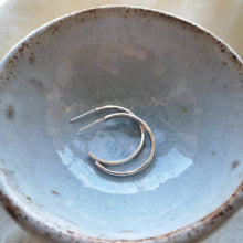 Load image into Gallery viewer, Side view of handmade sustainable silver hoops in a light blue glazed ceramic dish