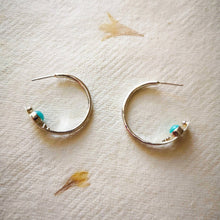 Load image into Gallery viewer, Hidden treasure handmade silver hoop earrings with aqua blue gemstones secret details, on cream paper with yellow flowers