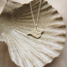 Load image into Gallery viewer, Three birds stamped on silver Isle of Wight shaped pendant, draped in a ceramic shell dish