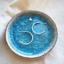 Load image into Gallery viewer, Handmade medium sized silver hoop earrings with scroll butterfly backs on blue glass and ceramic dish