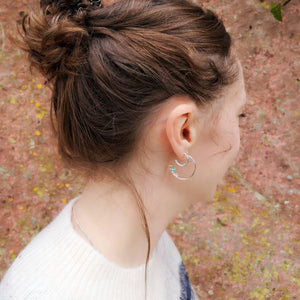 Eco silver hoop earrings, one mini classic pair, one hidden treasure hoops with blue stones, worn by woman with brown hair 