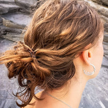 Load image into Gallery viewer, Wild wave recycled silver large ocean wave hoop earring, woman with hair in messy bun on Cornish beach with blue slate