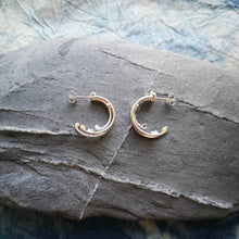 Load image into Gallery viewer, Small Wild Wave silver hoop earrings displaying both sides on a grey stone
