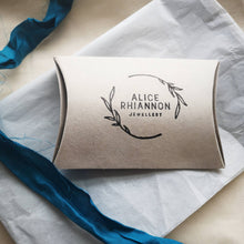 Load image into Gallery viewer, Natural recycled card pillow box with Alice Rhiannon Jewellery leaves logo, on white tissue paper, with peacock blue recycled sari ribbon