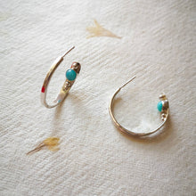 Load image into Gallery viewer, Textured eco silver hoop earrings with blue gemstones and silver balls inside hoop, on yellow and cream pressed flower paper 
