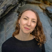 Load image into Gallery viewer, Woman wearing black top and unusual eco silver wave hoop earrings on Cornish beach