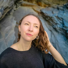 Load image into Gallery viewer, Blue slate cliff background with woman in black top wearing ocean themed jewellery ethical and sustainable hoops