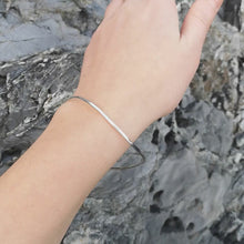 Load and play video in Gallery viewer, Video of recycled silver curved ripple bangle worn on moving around to show all angles