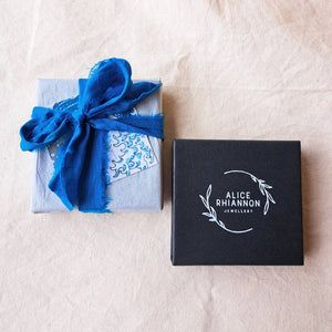 Black branded jewellery box, with another box wrapped in blue silk ribbon with wave business card