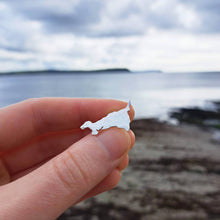 Load image into Gallery viewer, Cornwall map shaped silver brooch tie pin, held above Gerrans Bay Portscatho, with rocky beach sea and headland
