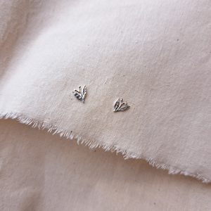 Silver leaf stud earrings with tiny berries, on plan natural fabric background