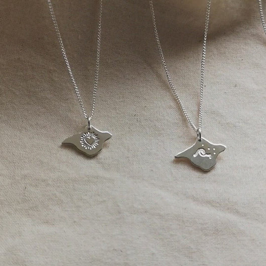Video of four Isle of Wight shaped silver necklaces with different designs engraved - heart, wave, birds and texture