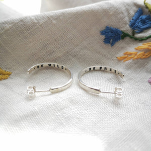 Silver textured hoop earrings with be wild be free message hand-stamped inside