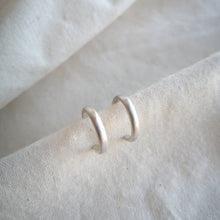 Load image into Gallery viewer, Silver hoops with brushed satin matte finish on calico fabric
