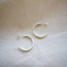 Load image into Gallery viewer, Side profile of textured simple silver hoop earrings on neutral background

