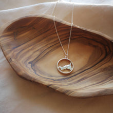 Load image into Gallery viewer, Cornwall map necklace lying inside wooden jewellery bowl on cream fabric background
