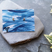 Load image into Gallery viewer, Half moon tiny eco silver studs on watercolour backing card of waves and a whale tail
