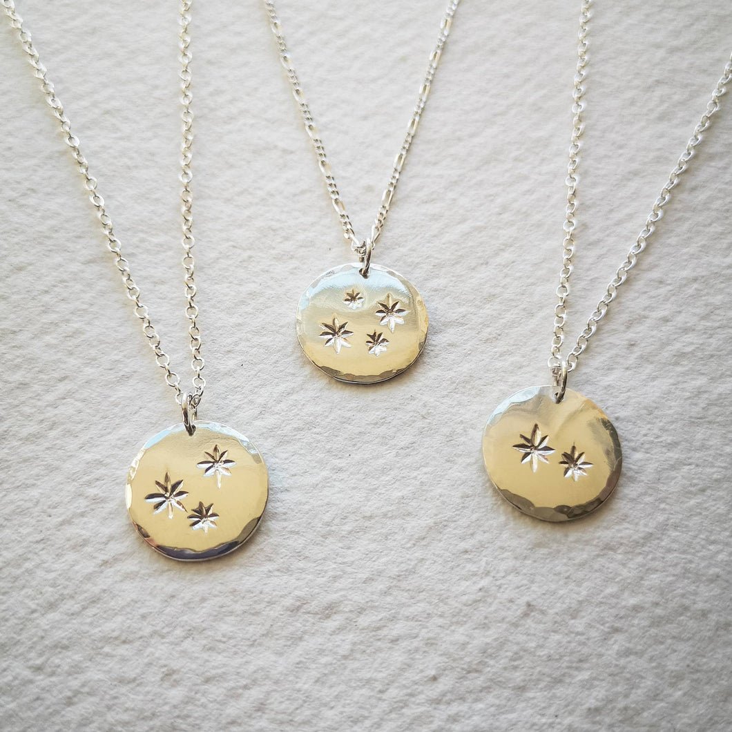 Three family star eco-silver disc necklaces with chains on natural cream paper background