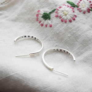 Silver hoops with hope and love inside on fabric with embroidered daisies