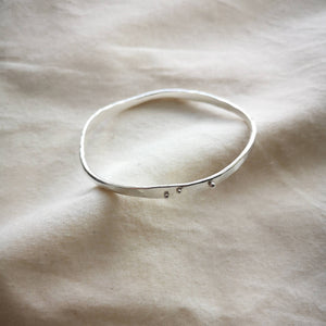 Sustainable recycled silver wave bangle, freefrom curves with silver balls for detail, on top of calico fabric