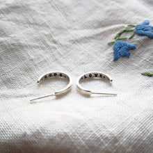 Load image into Gallery viewer, Mini eco silver hoops with hope and love messages inside, on fabric with blue flowers
