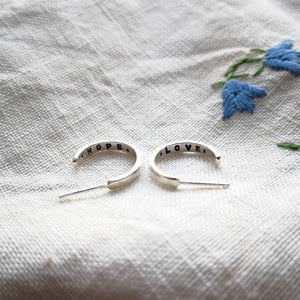 Mini eco silver hoops with hope and love messages inside, on fabric with blue flowers