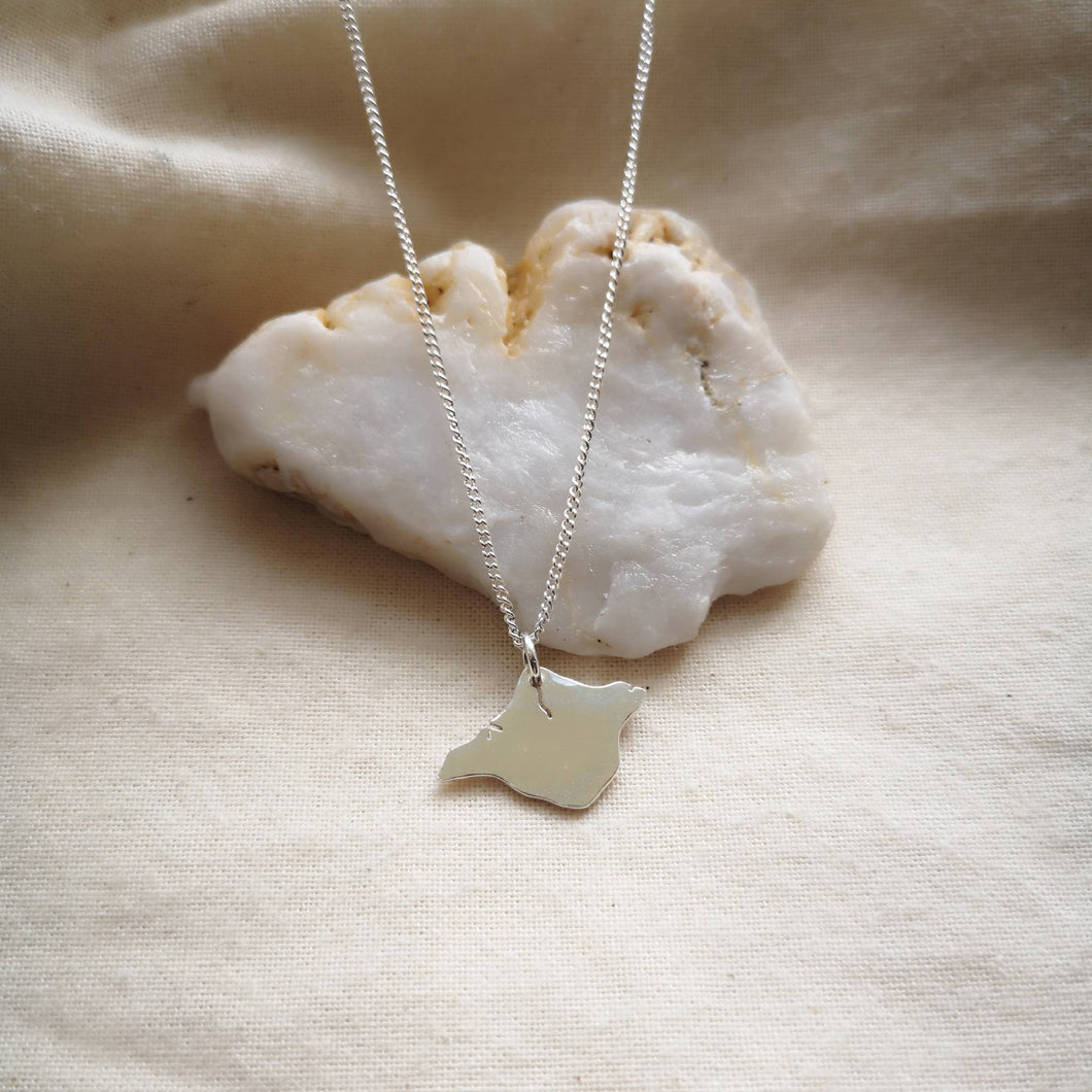 Recycled silver sustainable Isle of Wight necklace draped over white quartz stone on calico fabric