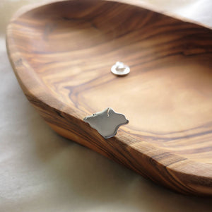 Sustainable recycled silver Isle of Wight pin with smooth shine finish, on edge of olive wood bowl