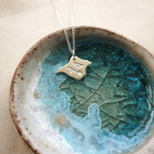 Load image into Gallery viewer, Silver Isle of Wight shaped necklace with three birds flying engraved, in blue and white glass dish
