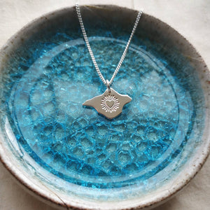 Silver heart Isle of Wight pendant with chain, lying in a blue crackle glass trinket dish 
