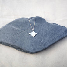 Load image into Gallery viewer, Isle of Wight silver necklace on chain hanging in middle of a grey stone on white fabric background
