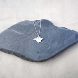 Isle of Wight silver necklace on chain hanging in middle of a grey stone on white fabric background