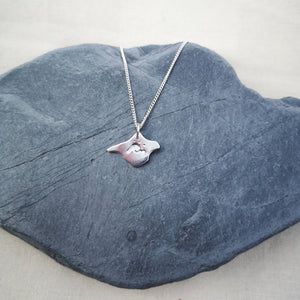 Surf inspired wave design on silver Isle of Wight shaped necklace, displayed on grey stone