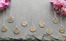 Load image into Gallery viewer, Selection of recycled silver antique-style love token coin necklaces on slate, including sunflower, arrows, whale &amp; infinity 
