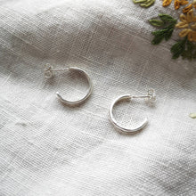 Load image into Gallery viewer, Mini recycled silver hoop earrings side profile on fabric with yellow embroidered flowers
