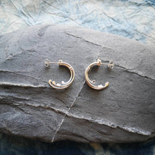 Load image into Gallery viewer, Small Wild Wave silver hoop earrings displaying both sides on a grey stone
