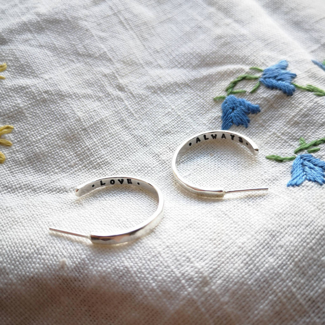 Silver hoop earrings with love always message stamped inside, on embroidered flower fabric blue flowers