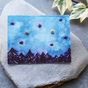 Full moon silver stud earrings on eco friendly backing card with a night forest and sky illustration in blue