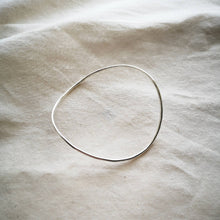 Load image into Gallery viewer, Sustainable recycled silver bangle, curved wavy shape, on plain natural cream fabric 
