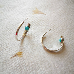 Textured eco silver hoop earrings with blue gemstones and silver balls inside hoop, on yellow and cream pressed flower paper 