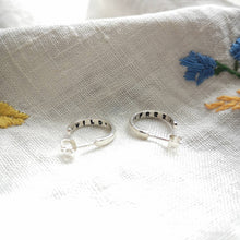 Load image into Gallery viewer, Mini silver hoops with wild and free stamped inside hoop, on embroidered flower fabric
