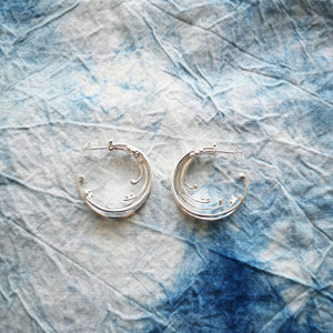 Sustainable recycled silver large wave hoop earrings, on tie dyed blue and white fabric